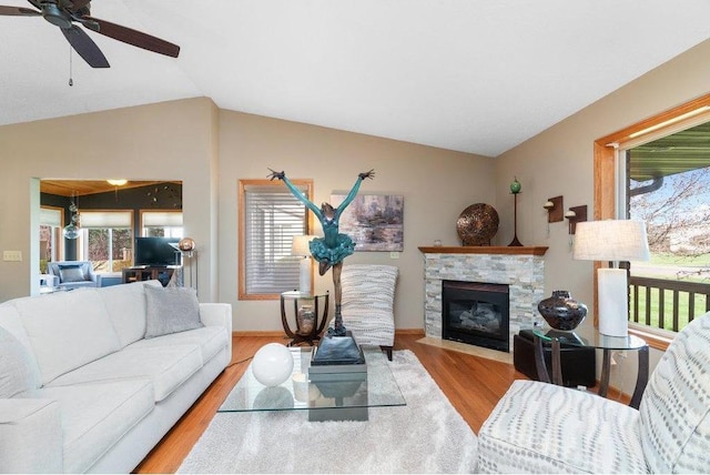 living room with a fireplace, light hardwood / wood-style flooring, vaulted ceiling, and a wealth of natural light