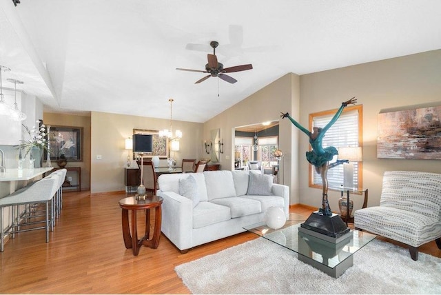 living room featuring ceiling fan with notable chandelier, light hardwood / wood-style floors, and vaulted ceiling