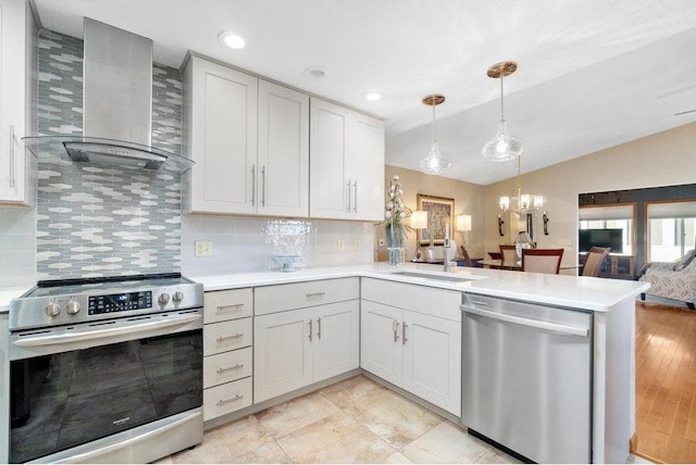 kitchen featuring appliances with stainless steel finishes, light wood-type flooring, wall chimney exhaust hood, sink, and hanging light fixtures