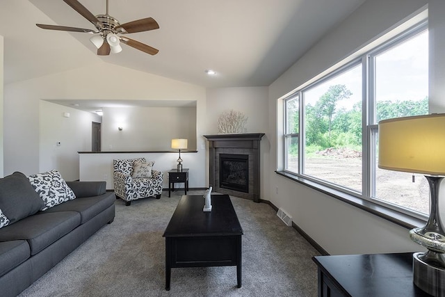 carpeted living room with a tile fireplace, vaulted ceiling, and ceiling fan