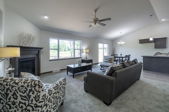 living room with carpet flooring, ceiling fan with notable chandelier, vaulted ceiling, and a fireplace