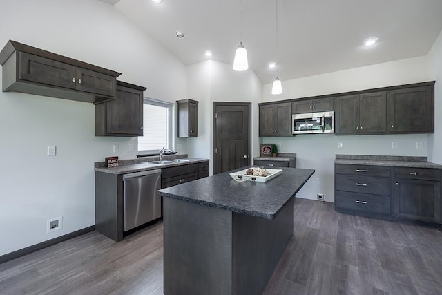 kitchen featuring appliances with stainless steel finishes, dark wood-type flooring, sink, pendant lighting, and a center island