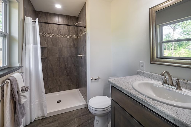 bathroom with a shower with curtain, a healthy amount of sunlight, toilet, and vanity