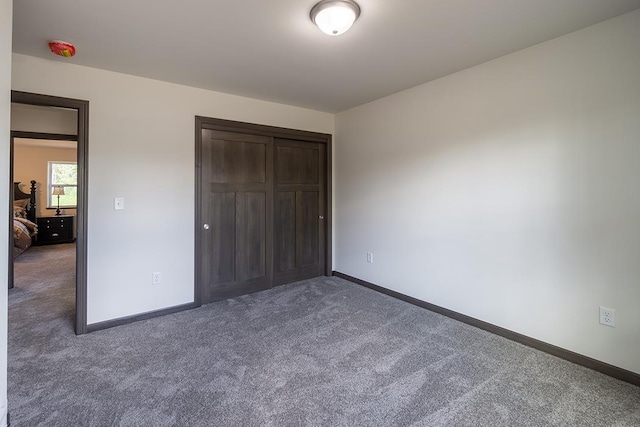 unfurnished bedroom featuring dark colored carpet and a closet