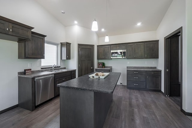 kitchen with dark hardwood / wood-style floors, a kitchen island, appliances with stainless steel finishes, and vaulted ceiling