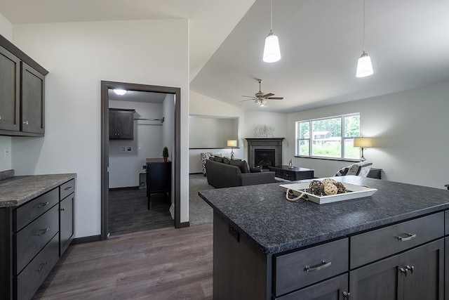 kitchen with ceiling fan, hanging light fixtures, dark hardwood / wood-style floors, vaulted ceiling, and a kitchen island