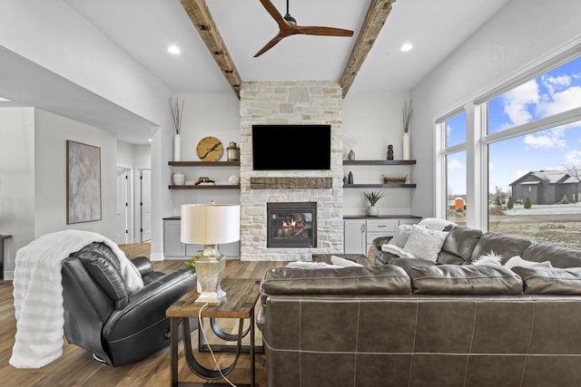 living room with ceiling fan, hardwood / wood-style floors, beamed ceiling, and a fireplace