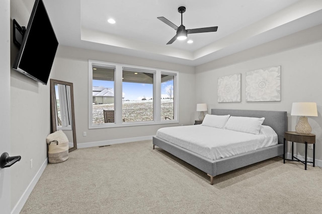 carpeted bedroom featuring ceiling fan and a raised ceiling