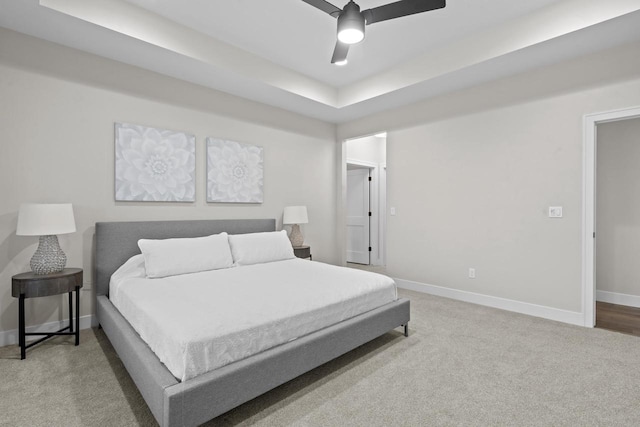 bedroom featuring ceiling fan, carpet, and a tray ceiling