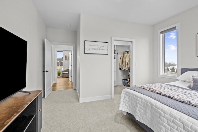 bedroom featuring light colored carpet, a closet, and a spacious closet