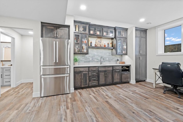 bar featuring dark brown cabinets, light hardwood / wood-style floors, decorative backsplash, and stainless steel fridge