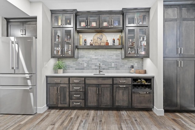 bar featuring dark brown cabinets, backsplash, dark hardwood / wood-style flooring, and stainless steel refrigerator