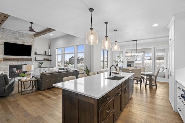 kitchen with dark brown cabinets, sink, white cabinets, an island with sink, and beamed ceiling