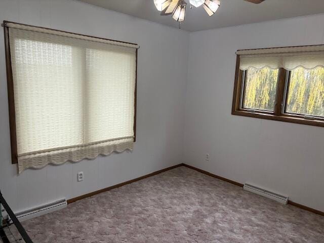 carpeted empty room with baseboard heating, ceiling fan, and plenty of natural light