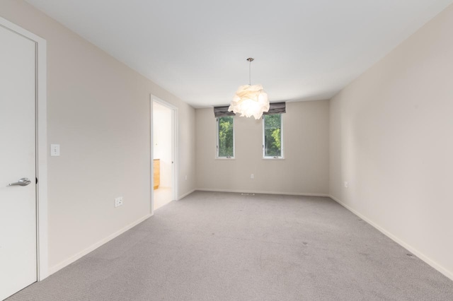 carpeted empty room with a notable chandelier