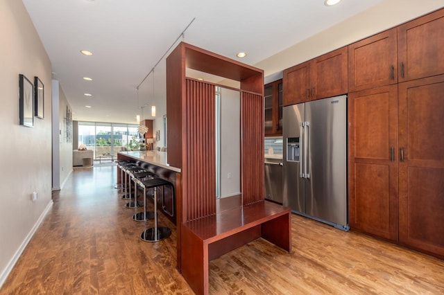 kitchen featuring a breakfast bar area, light hardwood / wood-style flooring, stainless steel appliances, and decorative light fixtures