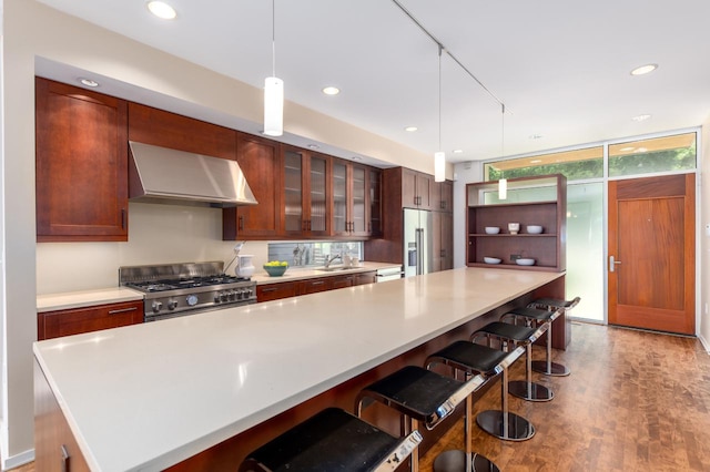 kitchen featuring pendant lighting, a breakfast bar, wall chimney exhaust hood, appliances with stainless steel finishes, and a large island