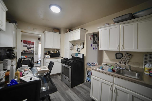 kitchen featuring white cabinets, hardwood / wood-style floors, gas stove, and sink