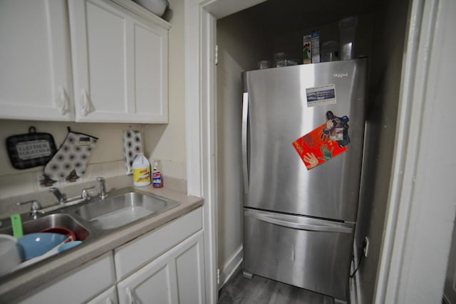 4828 N 25th St, Milwaukee, WI 53209 - kitchen with freestanding refrigerator, white cabinetry, dark wood-style floors, light countertops, and a sink