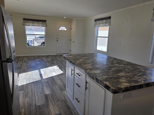 1407 N Peach Ave Unit 119, Marshfield, WI 54449 - kitchen with freestanding refrigerator, dark countertops, white cabinets, dark wood finished floors, and crown molding