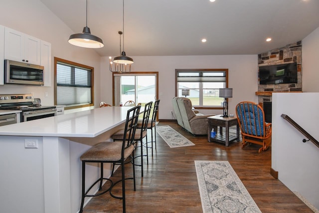 kitchen featuring stainless steel appliances, dark wood-type flooring, white cabinets, a center island, and hanging light fixtures