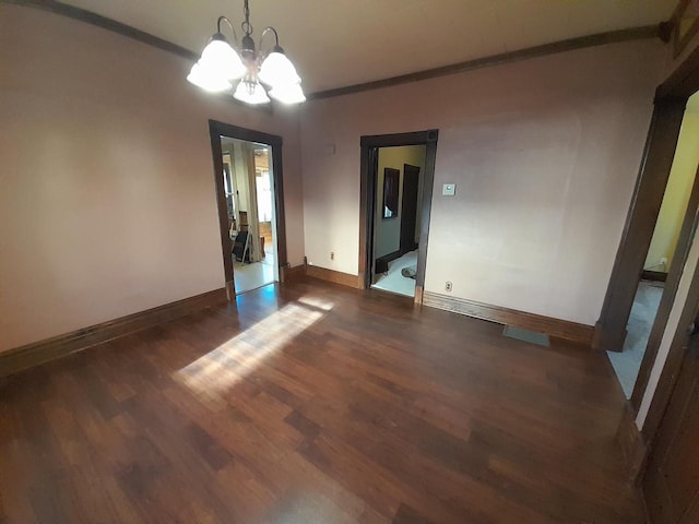 spare room featuring dark hardwood / wood-style floors and an inviting chandelier