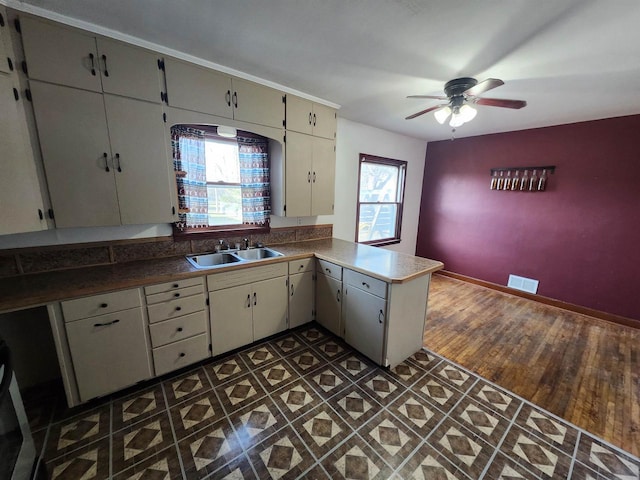 kitchen featuring kitchen peninsula, dark hardwood / wood-style flooring, a wealth of natural light, and sink