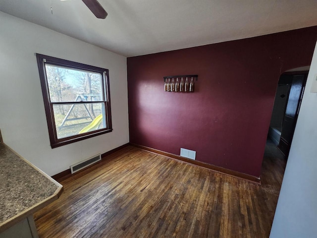 unfurnished room with ceiling fan and dark wood-type flooring