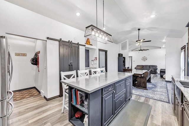 kitchen with pendant lighting, stainless steel refrigerator, a kitchen breakfast bar, a kitchen island, and a barn door