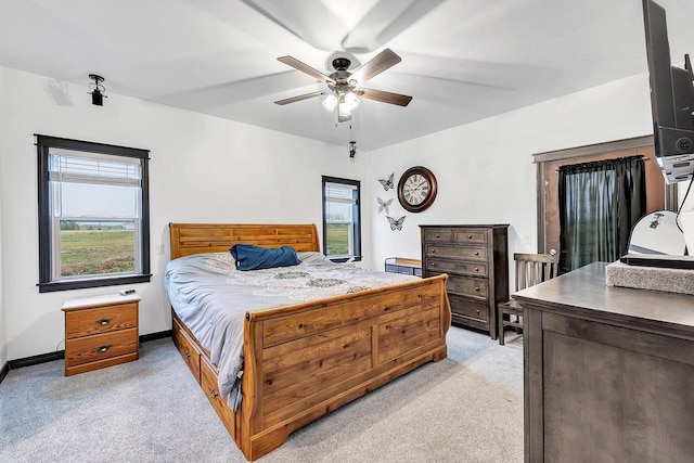 bedroom featuring multiple windows, light colored carpet, and ceiling fan