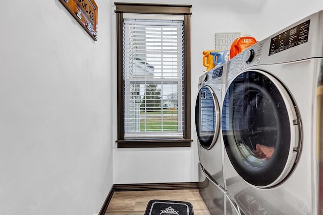 laundry area with washer and clothes dryer and light hardwood / wood-style flooring