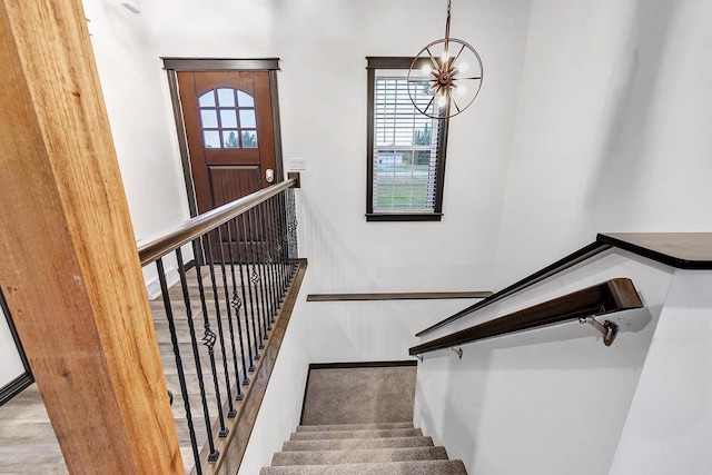 staircase with an inviting chandelier and a healthy amount of sunlight