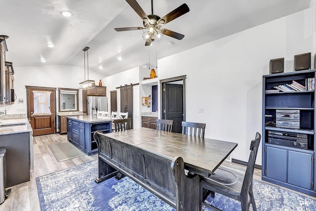 interior space with lofted ceiling, sink, light hardwood / wood-style flooring, ceiling fan, and a barn door