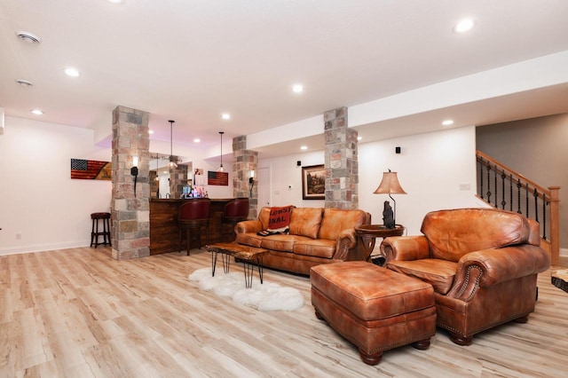 living room featuring decorative columns, bar, and light wood-type flooring