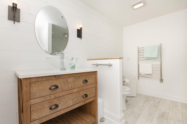 bathroom featuring radiator heating unit, toilet, vanity, tile walls, and hardwood / wood-style flooring