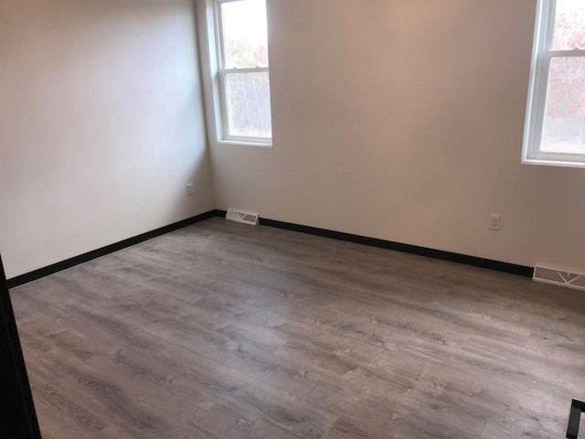 empty room with light hardwood / wood-style floors and a healthy amount of sunlight