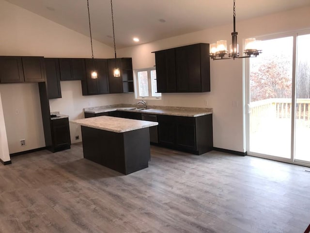 kitchen with wood-type flooring, decorative light fixtures, a chandelier, a center island, and lofted ceiling