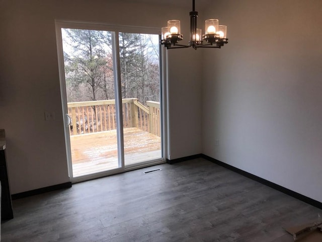 unfurnished dining area featuring a notable chandelier and dark wood-type flooring