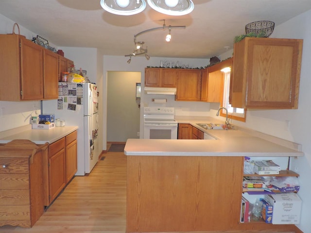 kitchen with kitchen peninsula, sink, white appliances, and light hardwood / wood-style flooring