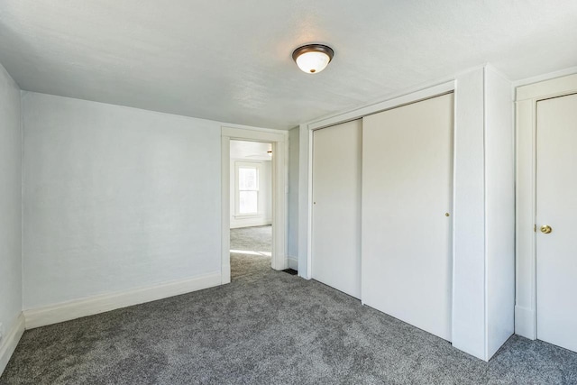 unfurnished bedroom with a closet, dark carpet, and a textured ceiling