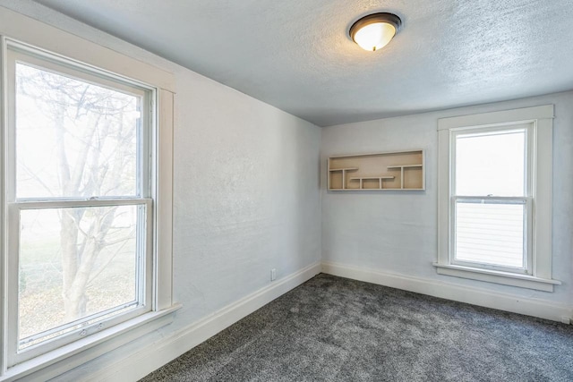 spare room featuring dark colored carpet and a textured ceiling