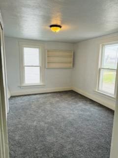 unfurnished room with dark colored carpet and a wealth of natural light