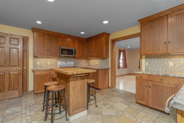 kitchen featuring a kitchen breakfast bar, decorative backsplash, a center island, and range