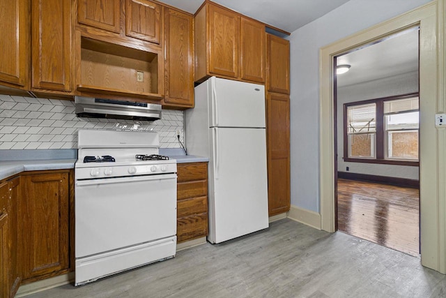 kitchen featuring decorative backsplash, range hood, white appliances, and light wood-type flooring