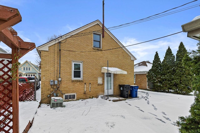 snow covered rear of property featuring central air condition unit