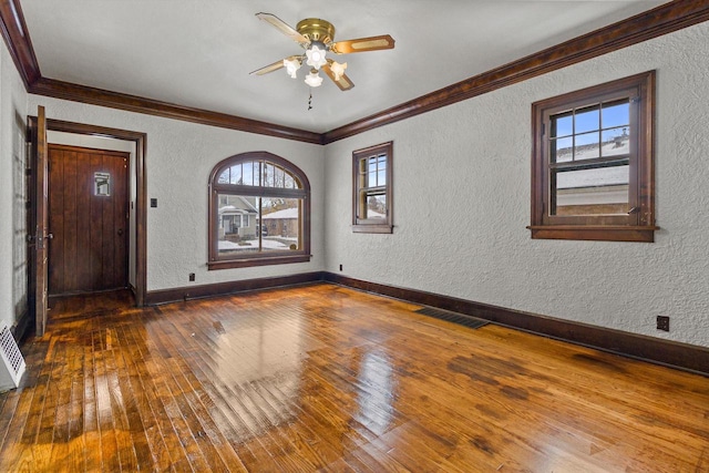 spare room with ceiling fan, dark wood-type flooring, a healthy amount of sunlight, and ornamental molding