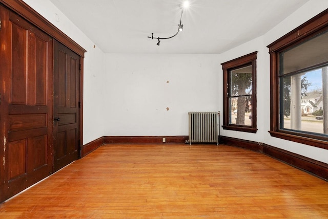 spare room featuring light wood-type flooring and radiator