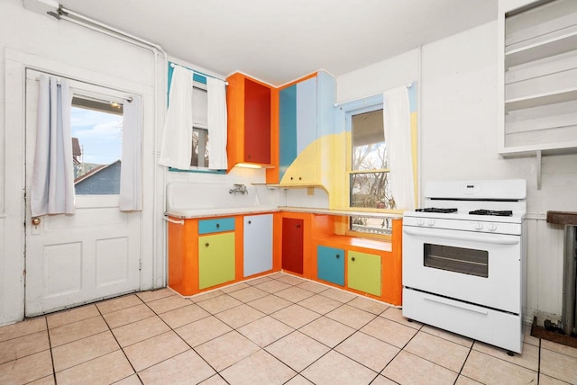 kitchen with tasteful backsplash, light tile patterned floors, white range oven, and a wealth of natural light