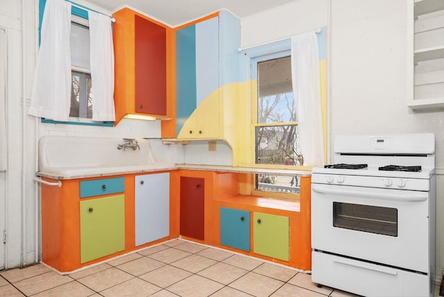 kitchen with backsplash, light tile patterned floors, and white gas range oven