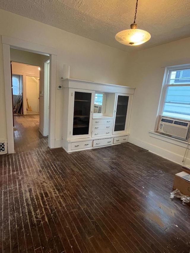 unfurnished bedroom featuring a textured ceiling, dark hardwood / wood-style flooring, and cooling unit